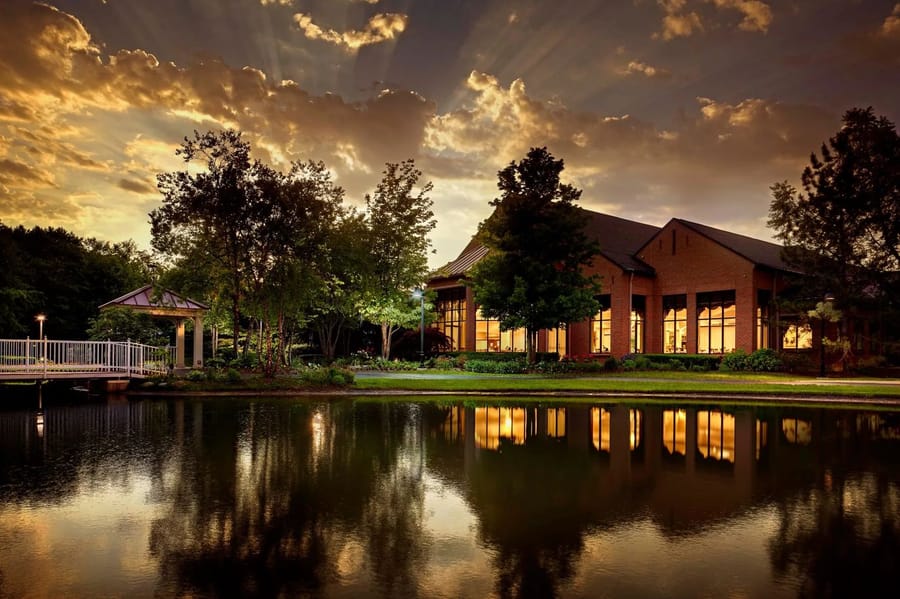 A senior living community at golden hour beside a landscaped pond